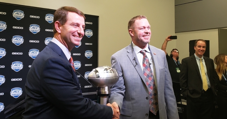 Swinney and Mendenhall shake hands in front of the ACC Championship Trophy.